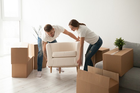 Young couple carrying chair to first shared apartment